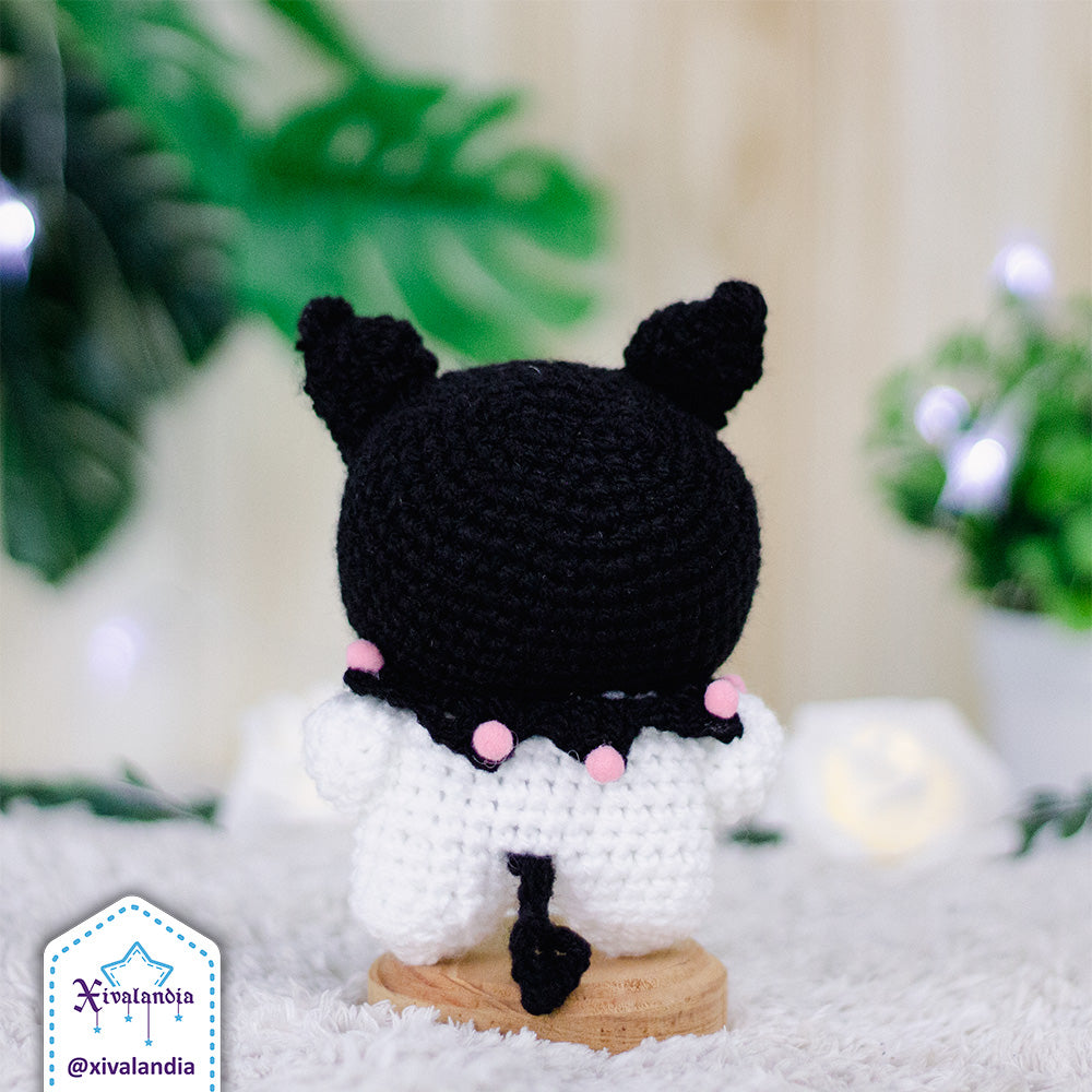 Peluche Kuromi de espaldas, con gorro en color negro. Mide 11 cm de alto, hecho a mano a crochet con estambre acrílico, ojos plásticos a presión y relleno sintético de poliéster. suave al tacto, ideal para coleccionar o decorar.